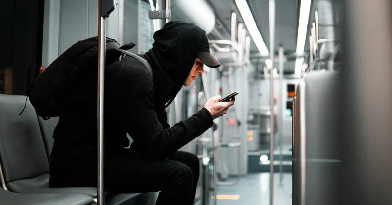 Commuter in all black with a black backpack on a metro train