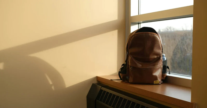 Leather work backpack on an office windowsill in warm morning light