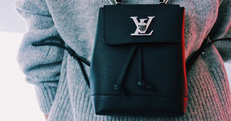 Person wearing a black Louis Vuitton Lockme mini backpack in grained leather over a grey knit sweater