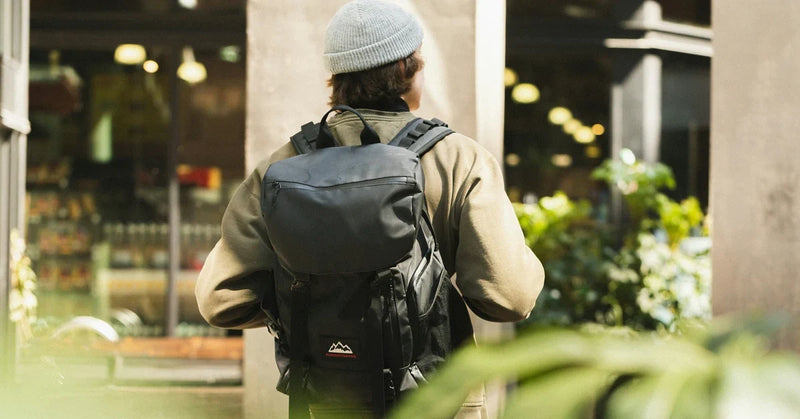 Commuter seen from behind on a city street wearing a black work backpack on both shoulders