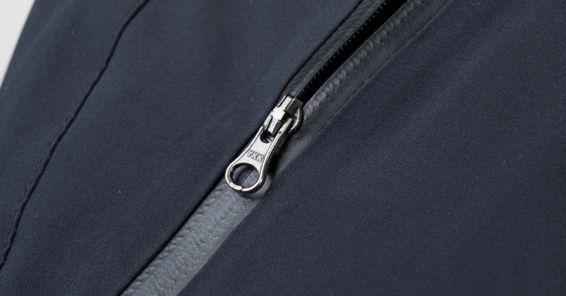 A silver YKK slider on a coated water-resistant zip on navy technical fabric