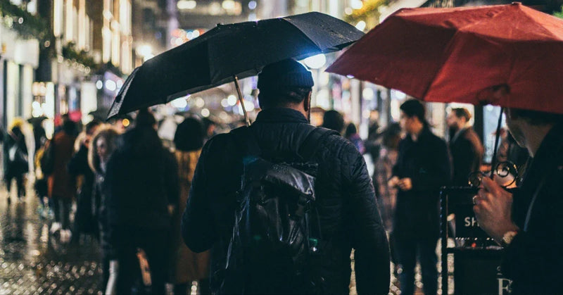 A person with a backpack walking through the rain at night in the city
